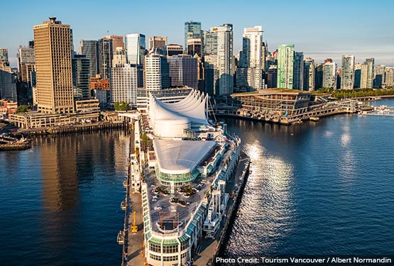 An aerial view of downtown Vancouver with the white sails of Canada Place on a pier.