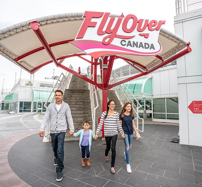 A family walks underneath the FlyOver Canada sign outside