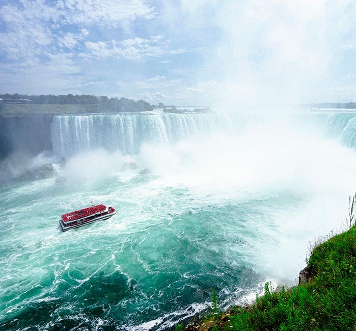 A red boat floats close to Niagara Falls.
