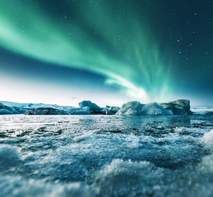 A sheet of ice in water, with green aurora borealis above.