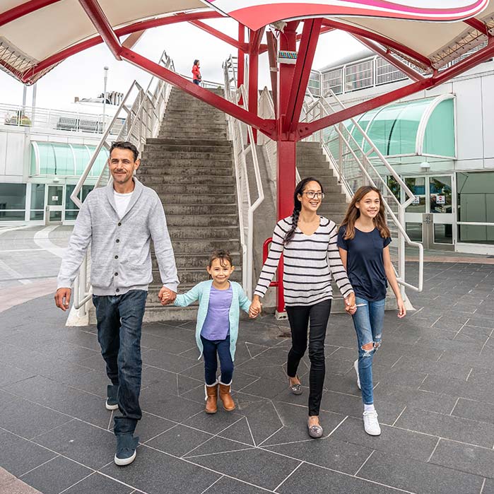 A family walks underneath the Flyover Canada sign outside